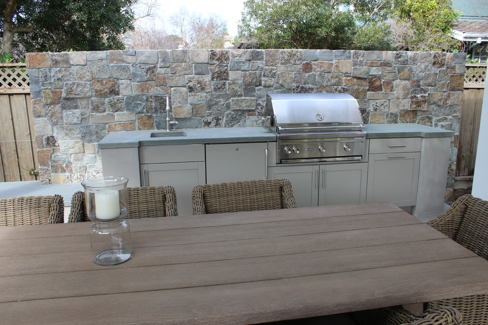 This is an example of a mid-sized traditional backyard patio in San Francisco with an outdoor kitchen, natural stone pavers and a roof extension.