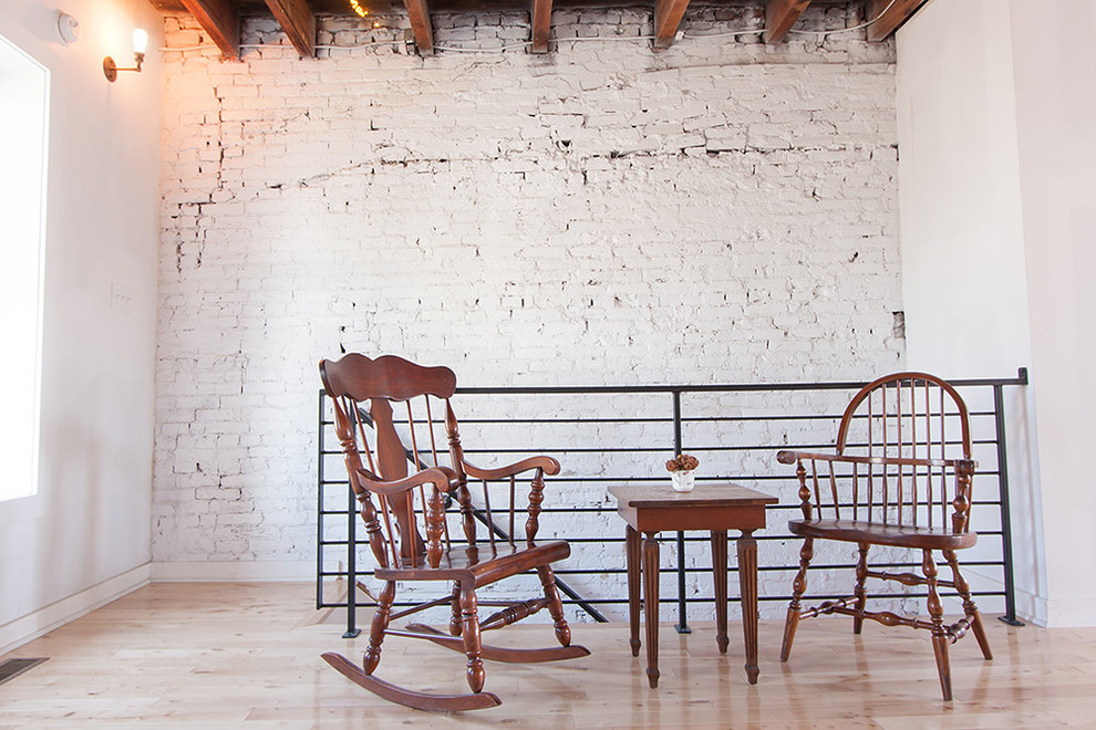 Inspiration for a large industrial loft-style bedroom in Philadelphia with white walls and light hardwood floors.