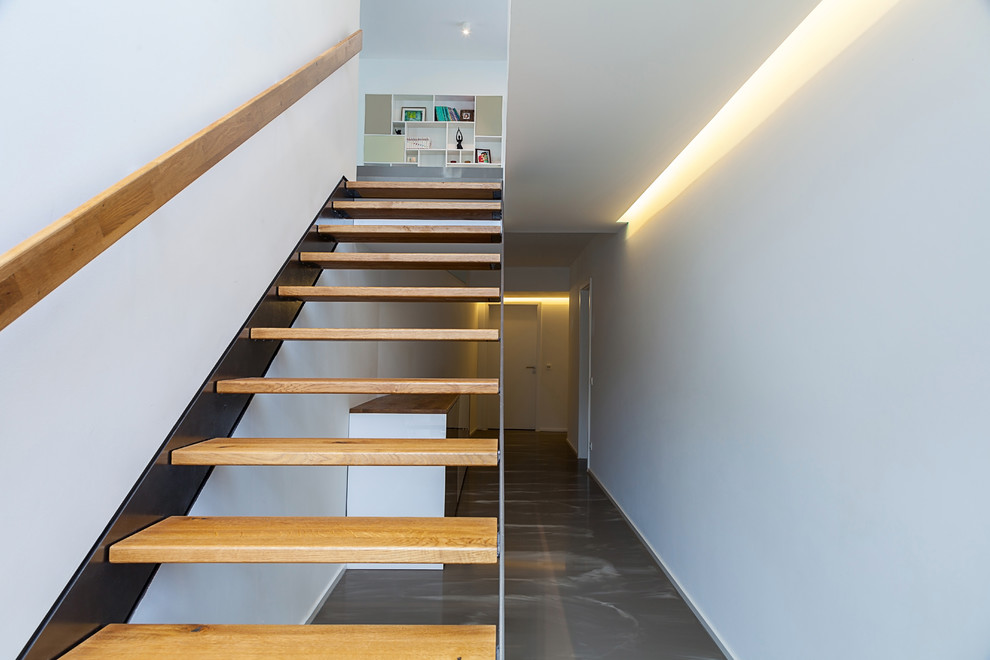 Small modern wood straight staircase in Dusseldorf with wood railing.