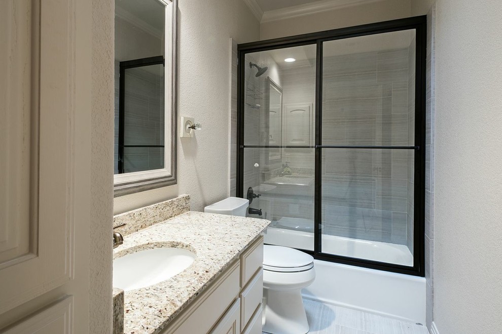 Small transitional kids bathroom in Austin with an undermount sink, beaded inset cabinets, white cabinets, granite benchtops, an alcove tub, a shower/bathtub combo, a two-piece toilet, gray tile, porcelain tile, beige walls and porcelain floors.