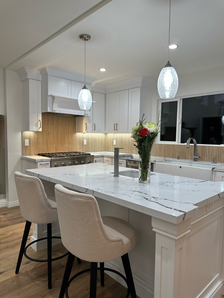 This is an example of an expansive asian eat-in kitchen in Los Angeles with a farmhouse sink, shaker cabinets, white cabinets, quartzite benchtops, brown splashback, porcelain splashback, stainless steel appliances, dark hardwood floors, with island and white benchtop.