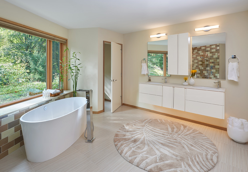 Photo of a large contemporary master bathroom in Detroit with flat-panel cabinets, white cabinets, a freestanding tub, an alcove shower, beige tile, brown tile, subway tile, beige walls, vinyl floors, an undermount sink and solid surface benchtops.