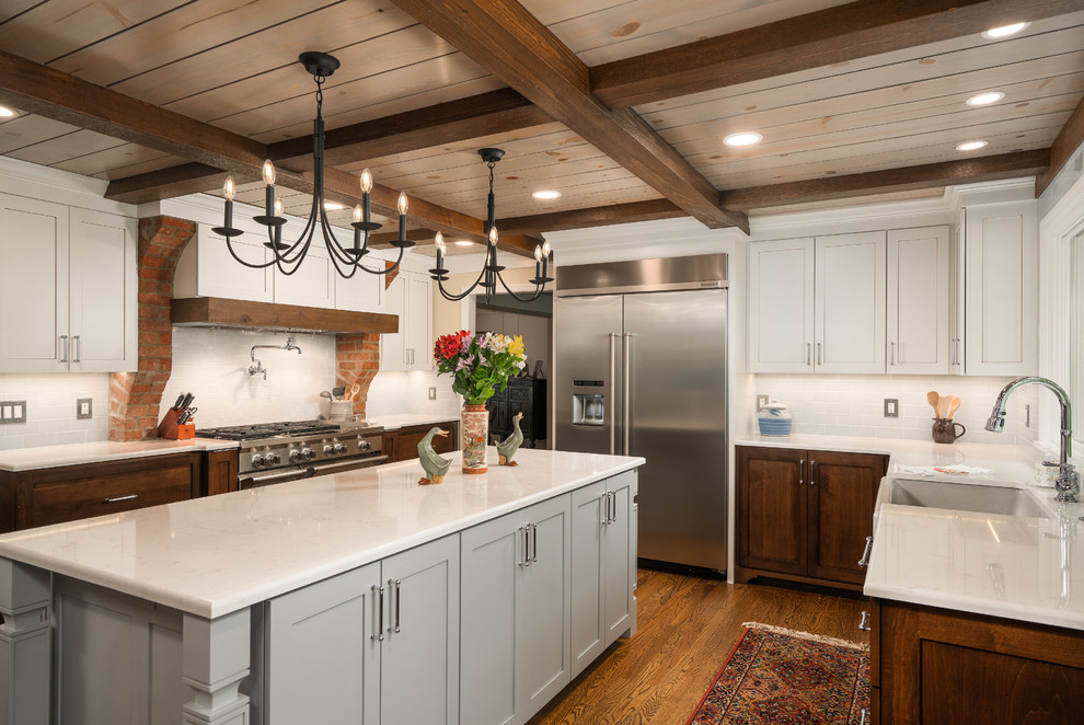 Eat-in kitchen - mid-sized transitional galley medium tone wood floor and brown floor eat-in kitchen idea in Columbus with a farmhouse sink, shaker cabinets, dark wood cabinets, quartz countertops, white backsplash, subway tile backsplash, stainless steel appliances, an island and white countertops