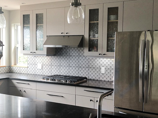 Example of a large eclectic u-shaped laminate floor and brown floor eat-in kitchen design with an undermount sink, glass-front cabinets, gray cabinets, quartz countertops, multicolored backsplash, ceramic backsplash, stainless steel appliances, an island and black countertops