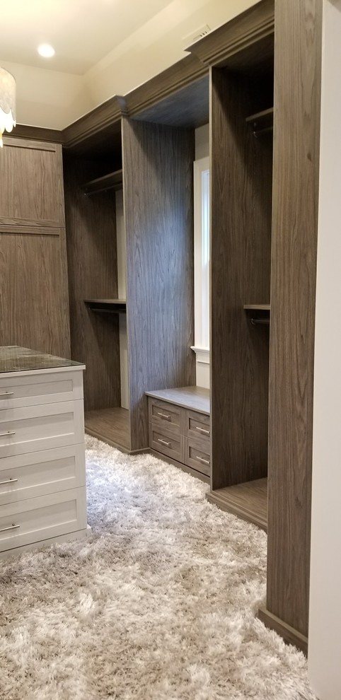 Photo of a large contemporary gender-neutral dressing room in New York with shaker cabinets, dark wood cabinets, carpet and beige floor.