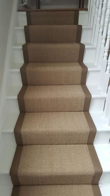 This is an example of a mid-sized transitional carpeted u-shaped staircase in London with carpet risers and wood railing.