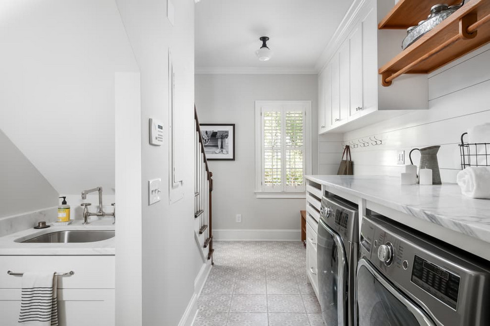 Mid-sized traditional single-wall utility room in Atlanta with a single-bowl sink, shaker cabinets, white cabinets, marble benchtops, grey walls, ceramic floors, a side-by-side washer and dryer, grey floor and white benchtop.