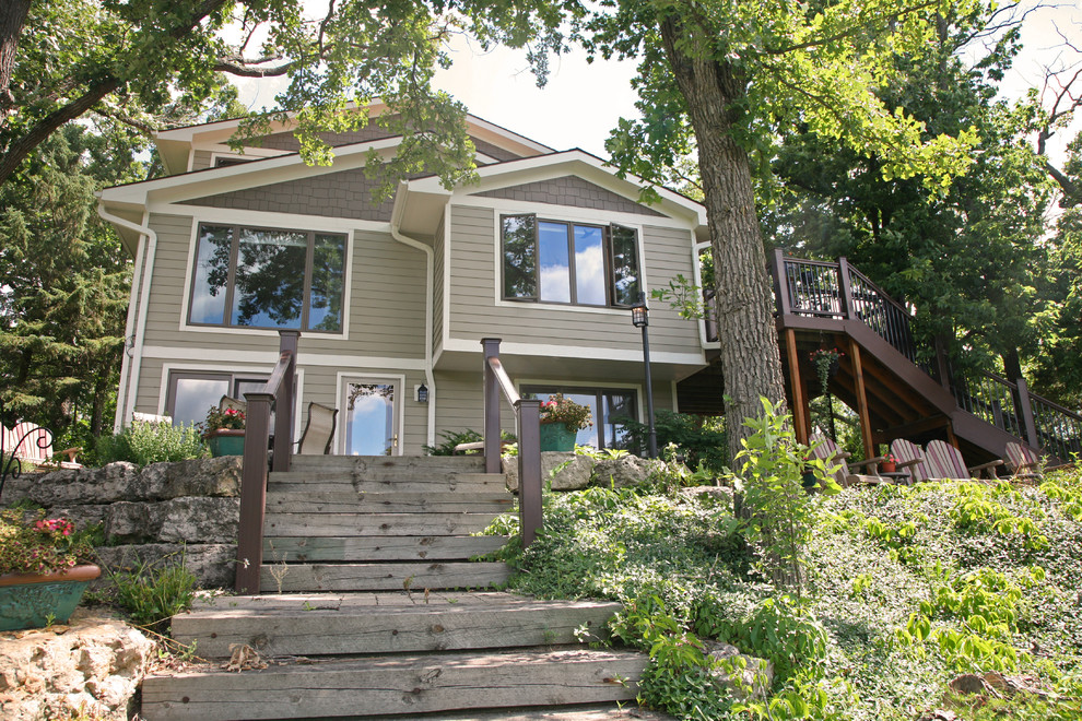 Photo of an expansive arts and crafts two-storey green house exterior in Milwaukee with concrete fiberboard siding, a gable roof and a shingle roof.
