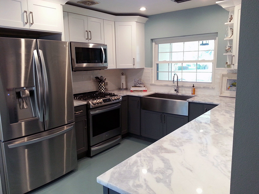 Photo of a small modern u-shaped eat-in kitchen in Orlando with a farmhouse sink, shaker cabinets, white cabinets, marble benchtops, white splashback, subway tile splashback, stainless steel appliances, concrete floors, no island and blue floor.