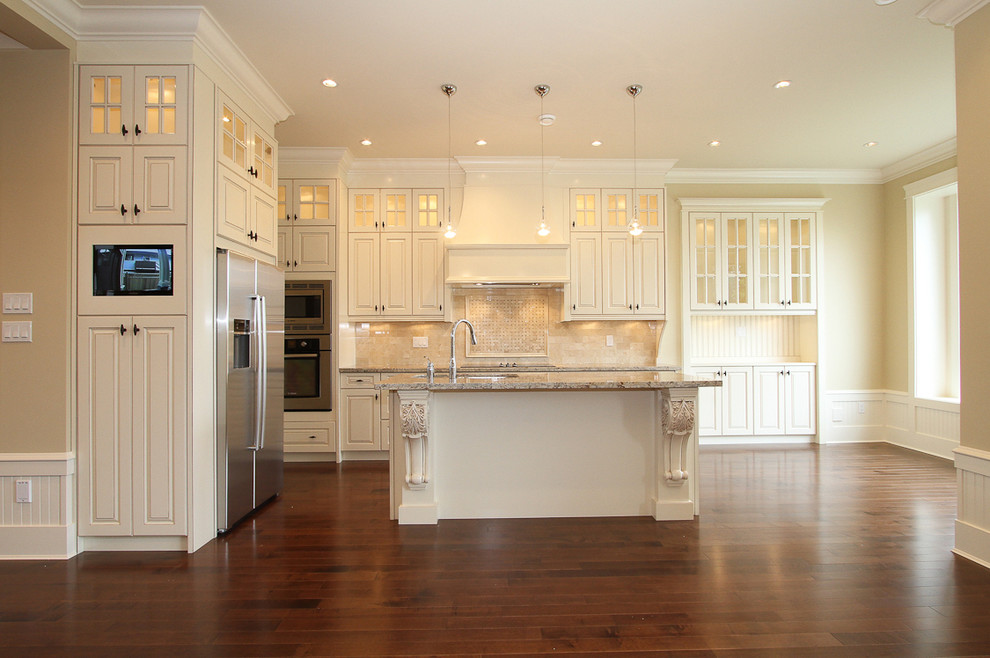 Large transitional l-shaped medium tone wood floor open concept kitchen photo in Vancouver with a drop-in sink, glass-front cabinets, white cabinets, granite countertops, beige backsplash, mosaic tile backsplash, stainless steel appliances and an island