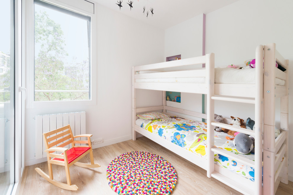 Inspiration for a mid-sized scandinavian gender-neutral kids' bedroom for kids 4-10 years old in Barcelona with white walls and light hardwood floors.