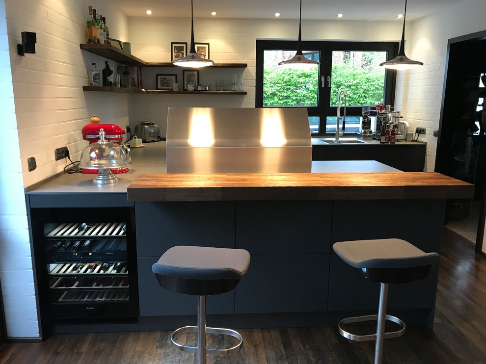 Photo of a large industrial u-shaped eat-in kitchen in Other with an integrated sink, flat-panel cabinets, grey cabinets, quartz benchtops, white splashback, brick splashback, stainless steel appliances, dark hardwood floors, a peninsula and yellow benchtop.