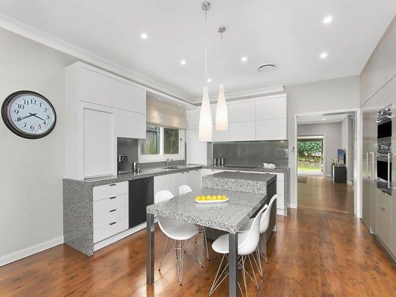 Photo of a mid-sized contemporary l-shaped eat-in kitchen in Sydney with an undermount sink, flat-panel cabinets, white cabinets, granite benchtops, grey splashback, glass sheet splashback, stainless steel appliances, medium hardwood floors, with island and brown floor.