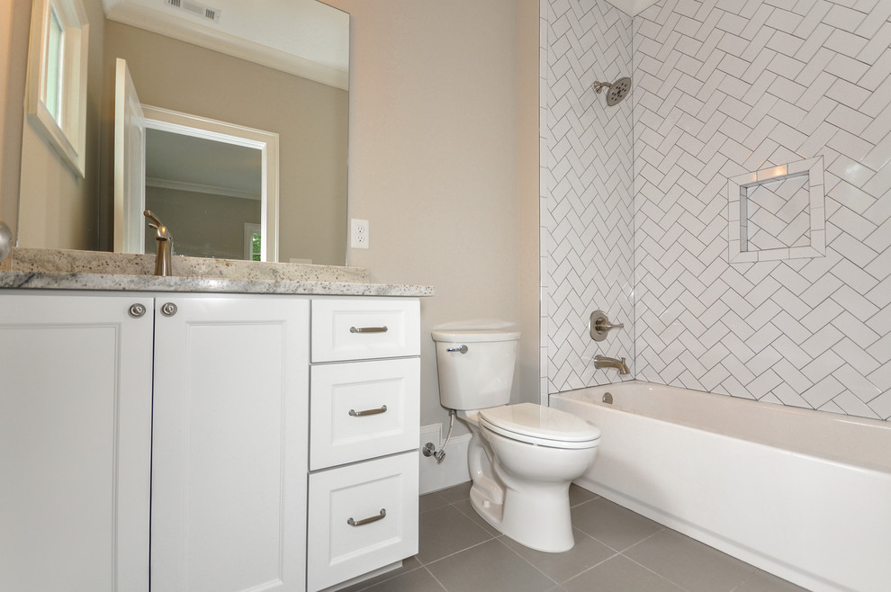 This is an example of a mid-sized traditional kids bathroom in Atlanta with an undermount sink, shaker cabinets, white cabinets, granite benchtops, an alcove tub, a shower/bathtub combo, a one-piece toilet, multi-coloured tile, ceramic tile, grey walls and ceramic floors.