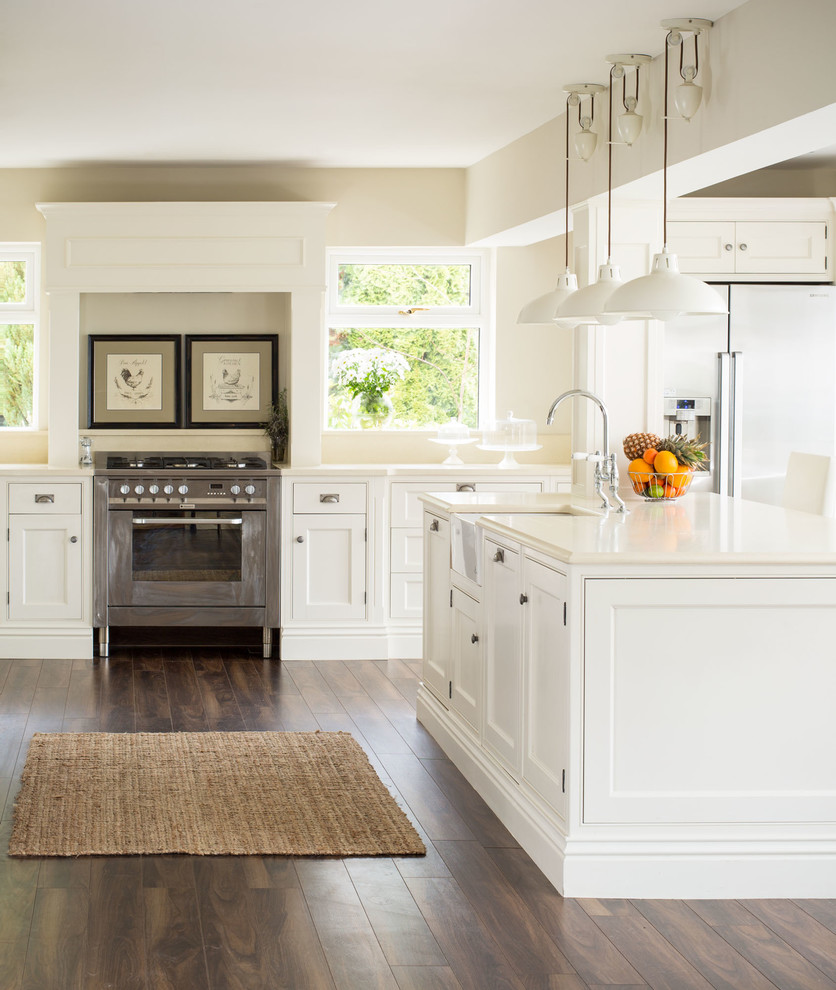 This is an example of a traditional eat-in kitchen in Dublin with a farmhouse sink, shaker cabinets, white cabinets, stainless steel appliances and dark hardwood floors.