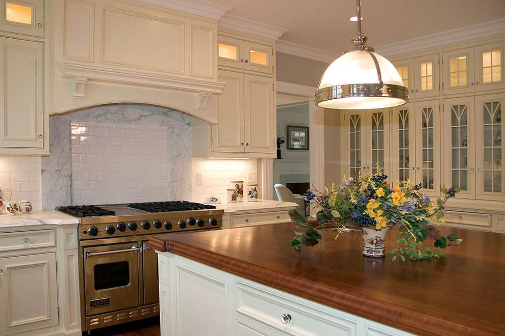 Photo of a large traditional l-shaped open plan kitchen in New York with an undermount sink, recessed-panel cabinets, white cabinets, panelled appliances, dark hardwood floors, with island and brown floor.
