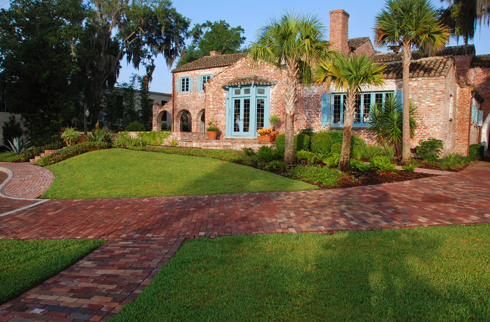 This is an example of a mediterranean front yard driveway in Orlando with brick pavers.