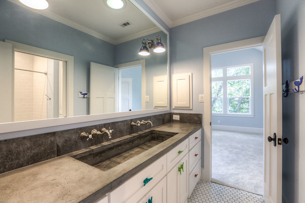 This is an example of a mid-sized transitional kids bathroom in Orange County with shaker cabinets, white cabinets, an alcove tub, a shower/bathtub combo, a one-piece toilet, white tile, subway tile, white walls, mosaic tile floors, an integrated sink and concrete benchtops.