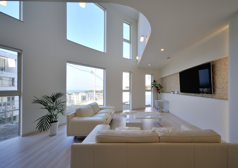 Beach style living room in Other with white walls, a wall-mounted tv and beige floor.