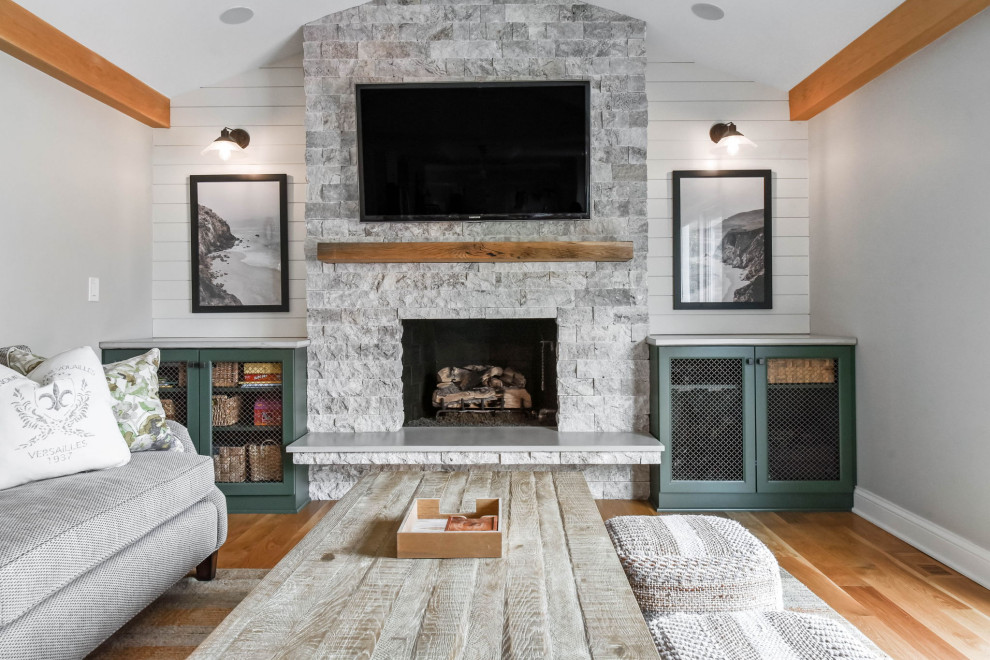 Medium sized country enclosed games room in Chicago with beige walls, light hardwood flooring, a standard fireplace, a stone fireplace surround, a wall mounted tv, exposed beams and tongue and groove walls.