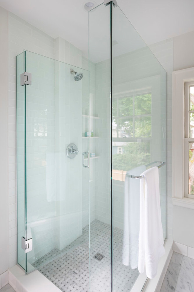 Photo of a mid-sized traditional master bathroom in Boston with recessed-panel cabinets, grey cabinets, a corner shower, a wall-mount toilet, white tile, glass tile, grey walls, marble floors, an undermount sink, marble benchtops, white floor and a hinged shower door.