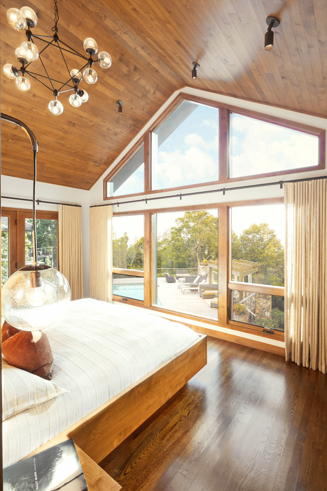 Inspiration for a large master medium tone wood floor, brown floor and wood ceiling bedroom remodel in Other with white walls and no fireplace