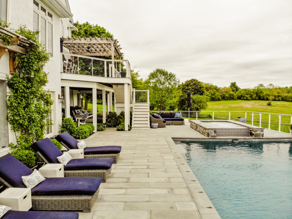 Photo of a large contemporary back rectangular infinity swimming pool in Philadelphia with a pool house and natural stone paving.