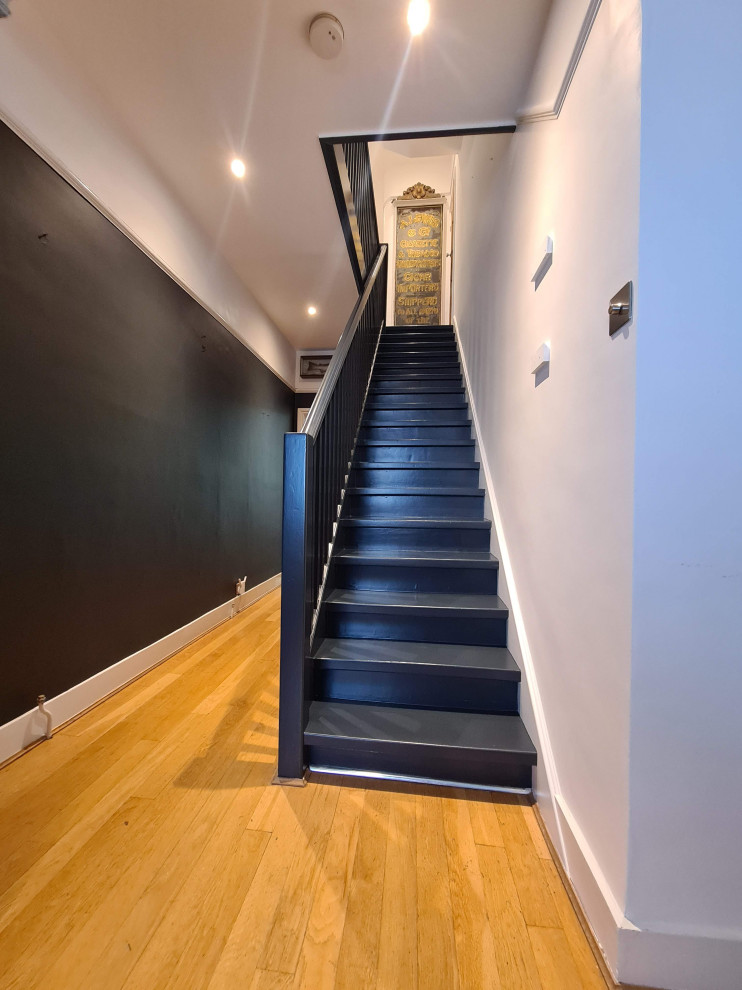 This is an example of an expansive traditional hallway in London with white walls, painted wood floors, black floor and recessed.