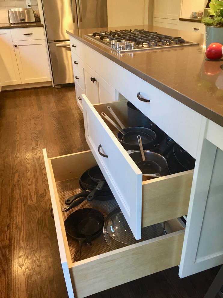 Photo of a mid-sized traditional l-shaped open plan kitchen in Portland with an undermount sink, shaker cabinets, white cabinets, quartz benchtops, beige splashback, subway tile splashback, stainless steel appliances, medium hardwood floors, with island and brown benchtop.