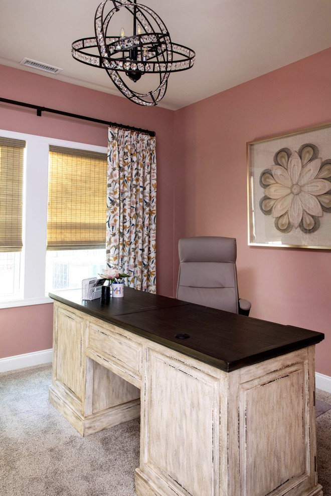 This is an example of a small transitional home office in Raleigh with pink walls, carpet, a freestanding desk and beige floor.