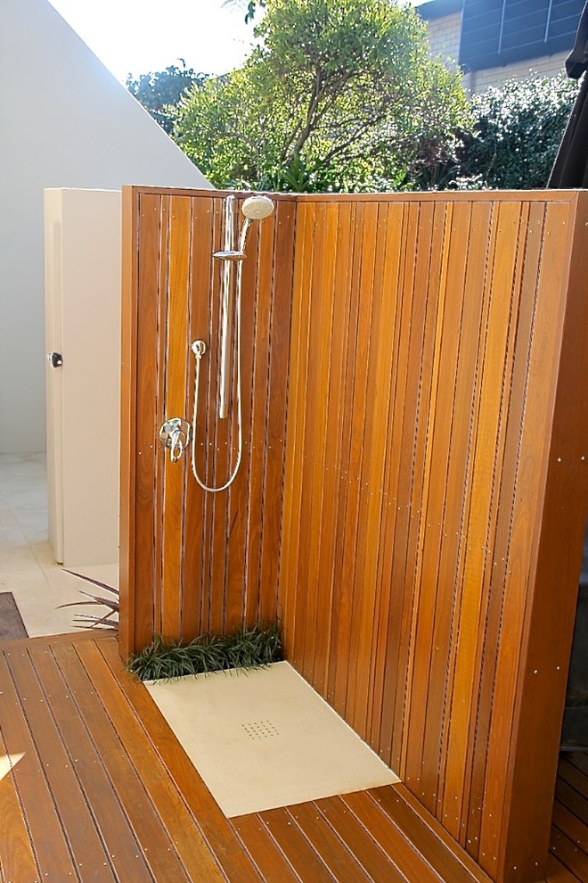 This is an example of a mid-sized beach style courtyard patio in Sydney with an outdoor shower, decking and a pergola.