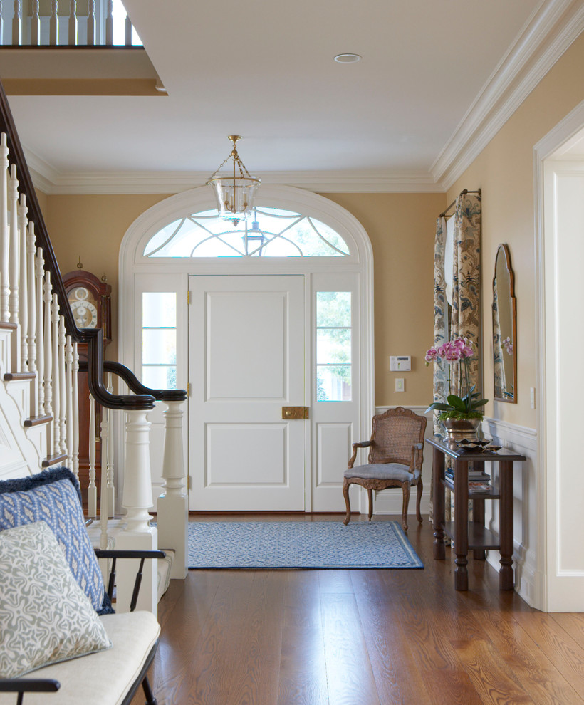 Inspiration for a traditional foyer in New York with yellow walls, medium hardwood floors, a single front door, a white front door and brown floor.