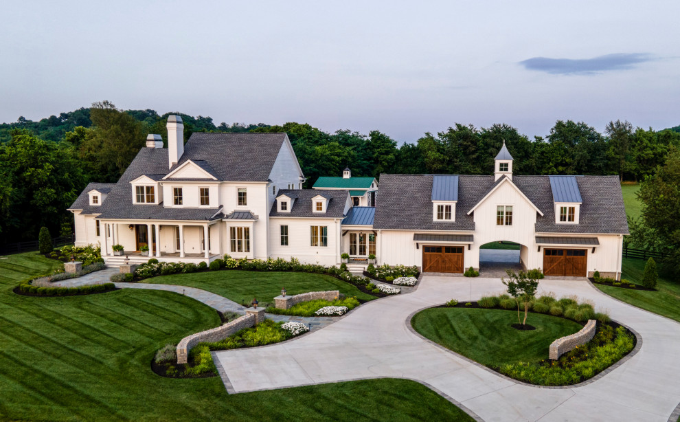 Foto della villa grande bianca country a due piani con rivestimenti misti, tetto a capanna, copertura mista, tetto grigio e pannelli e listelle di legno