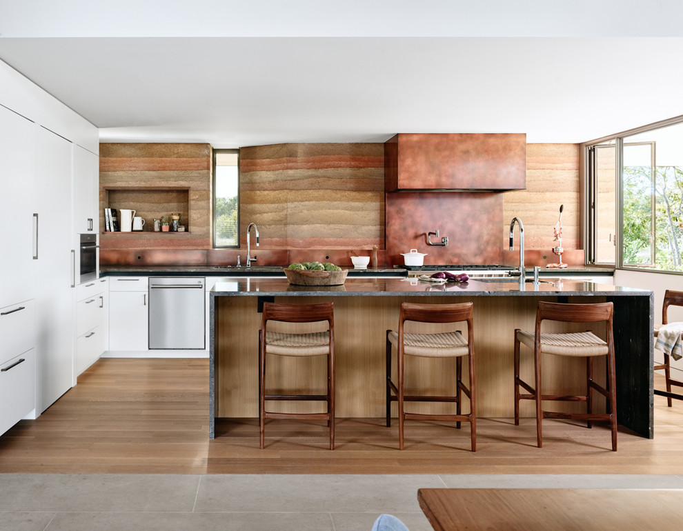 Inspiration for a l-shaped open plan kitchen in Other with flat-panel cabinets, white cabinets, granite benchtops, panelled appliances, with island, black benchtop, a single-bowl sink, multi-coloured splashback and light hardwood floors.