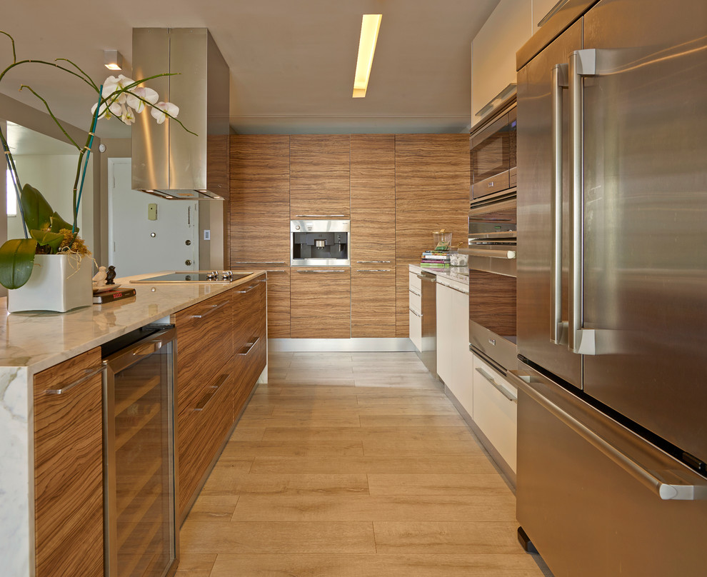 This is an example of a contemporary u-shaped kitchen in Miami with flat-panel cabinets, medium wood cabinets, stainless steel appliances, light hardwood floors and with island.