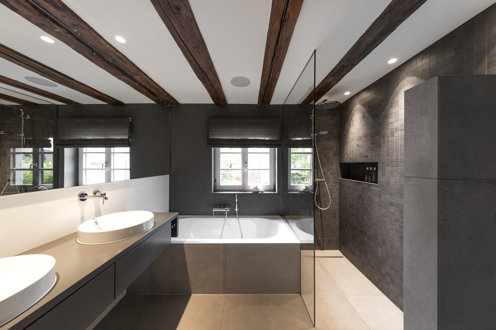 This is an example of a contemporary master bathroom in Stuttgart with flat-panel cabinets, grey cabinets, an alcove tub, an alcove shower, grey walls, an open shower, gray tile, a vessel sink, wood benchtops, grey floor and grey benchtops.