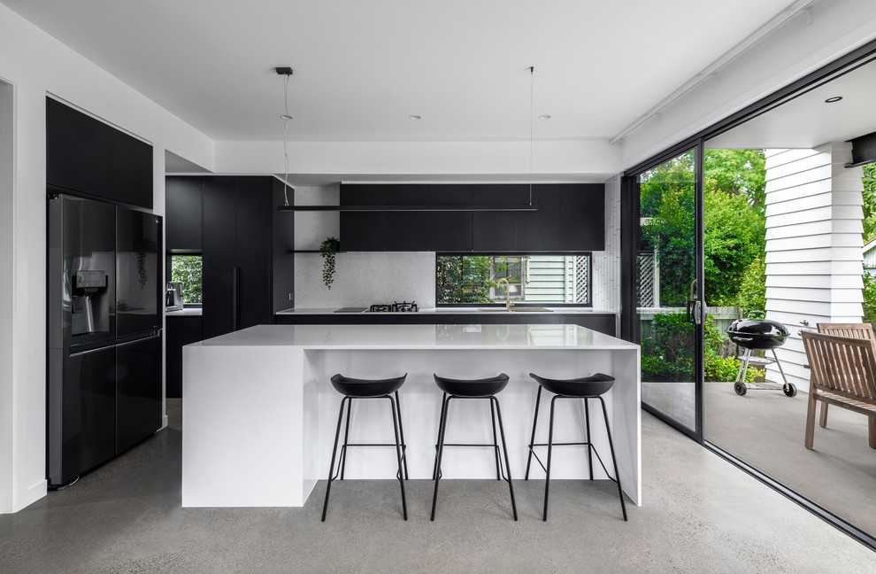 Inspiration for a large contemporary l-shaped eat-in kitchen in Brisbane with with island, an undermount sink, flat-panel cabinets, black cabinets, grey splashback, stainless steel appliances, concrete floors, grey floor and white benchtop.