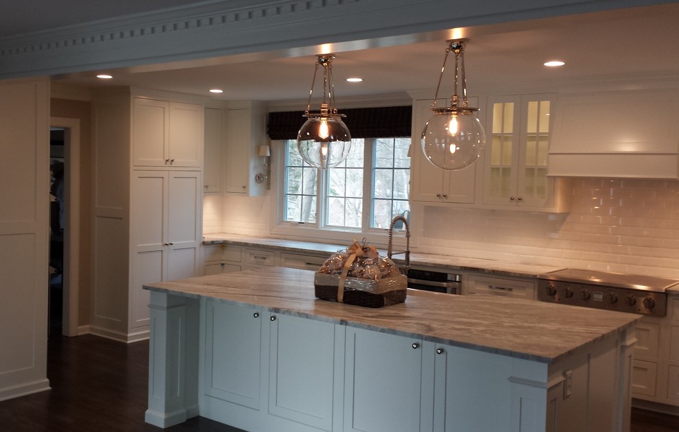 Example of a large transitional u-shaped dark wood floor enclosed kitchen design with a farmhouse sink, shaker cabinets, white cabinets, marble countertops, white backsplash, subway tile backsplash, stainless steel appliances and an island