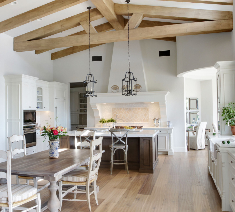 Design ideas for a traditional eat-in kitchen in Phoenix with a farmhouse sink, recessed-panel cabinets, white cabinets, beige splashback and panelled appliances.