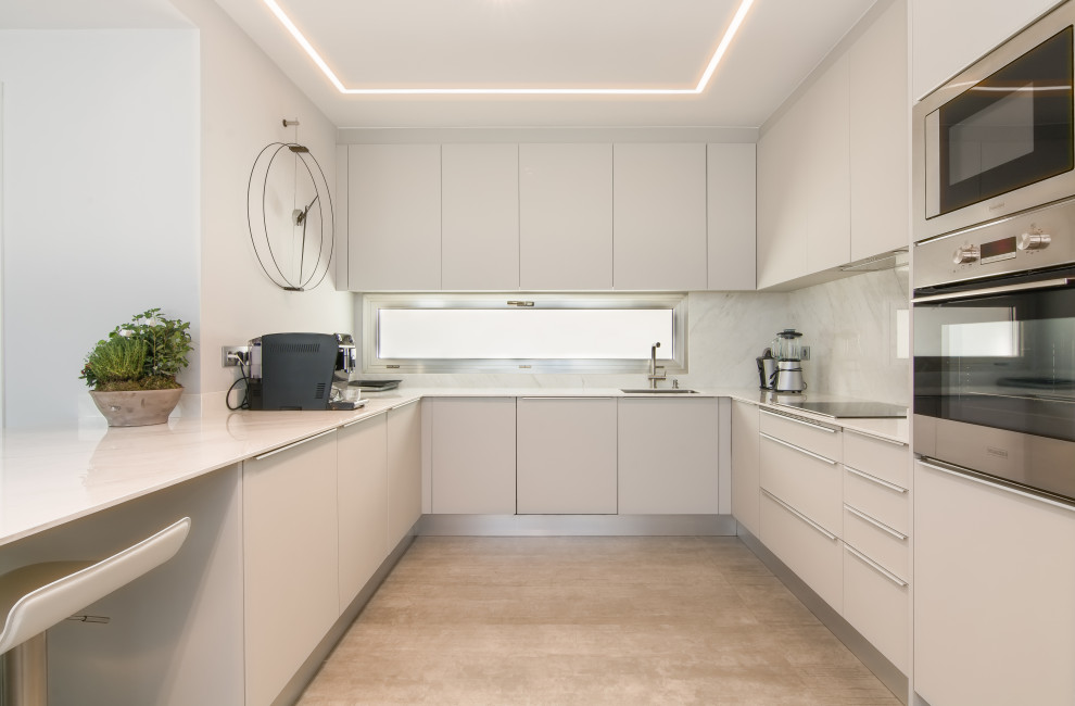 Design ideas for a mid-sized contemporary u-shaped kitchen in Other with an undermount sink, flat-panel cabinets, white cabinets, white splashback, stainless steel appliances, porcelain floors, a peninsula, grey floor and white benchtop.