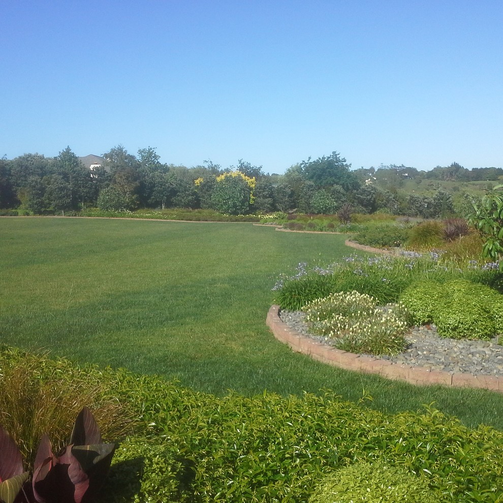 This is an example of an expansive country backyard full sun formal garden for summer in Auckland with mulch.