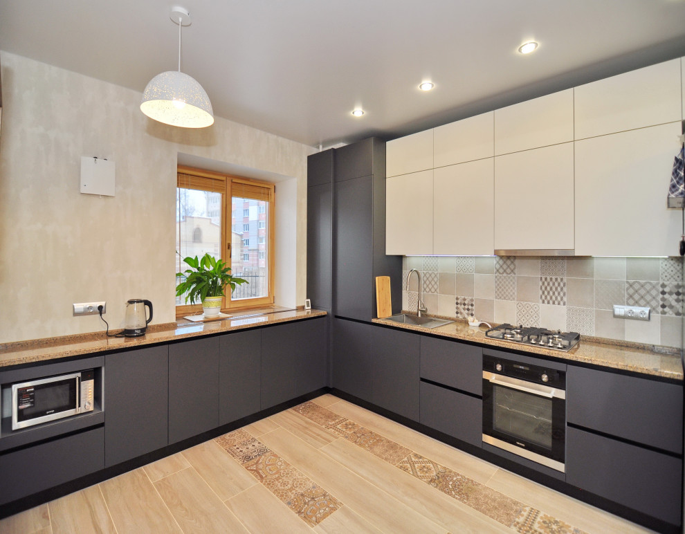 Modern inredning av ett mellanstort brun brunt kök, med en nedsänkt diskho, släta luckor, grå skåp, granitbänkskiva, beige stänkskydd, stänkskydd i keramik, svarta vitvaror, klinkergolv i keramik och beiget golv