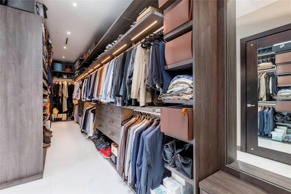 Photo of a large contemporary gender-neutral walk-in wardrobe in Miami with open cabinets, dark wood cabinets, marble floors and white floor.