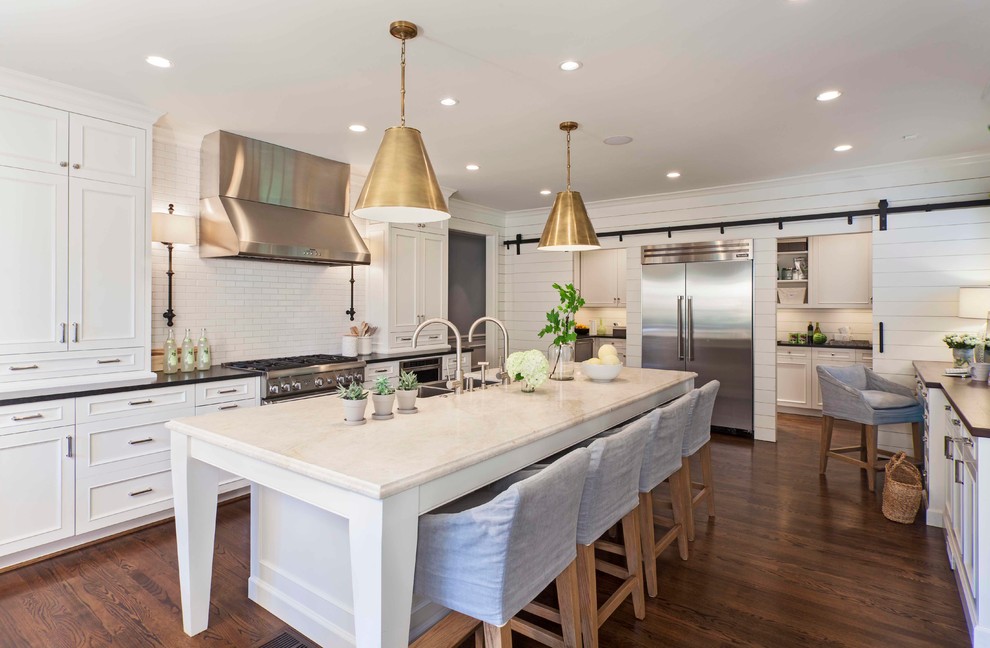 This is an example of a transitional kitchen in Charlotte with a double-bowl sink, recessed-panel cabinets, white cabinets, solid surface benchtops, white splashback, subway tile splashback, stainless steel appliances, with island and dark hardwood floors.