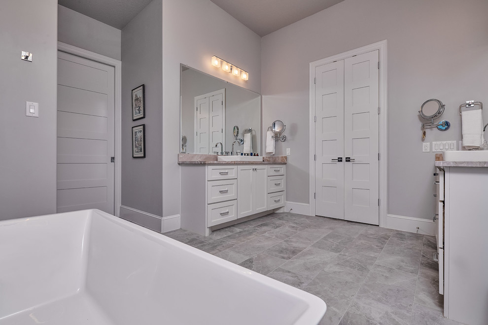 This is an example of a mid-sized modern master bathroom in Other with shaker cabinets, white cabinets, a freestanding tub, a one-piece toilet, grey walls, a vessel sink, grey floor and beige benchtops.