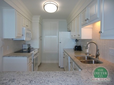 Photo of a small beach style u-shaped eat-in kitchen in Charleston with an undermount sink, raised-panel cabinets, white cabinets, granite benchtops, white splashback, subway tile splashback, white appliances and ceramic floors.