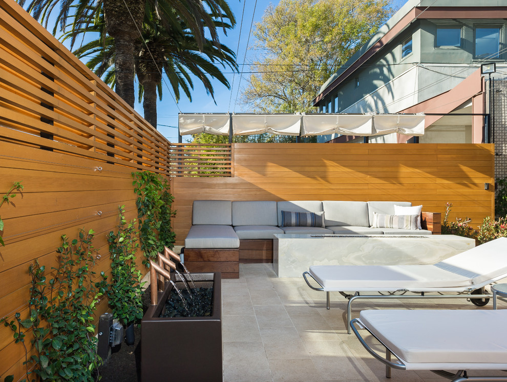 This is an example of a mid-sized modern front yard patio in Los Angeles with a water feature, tile and an awning.