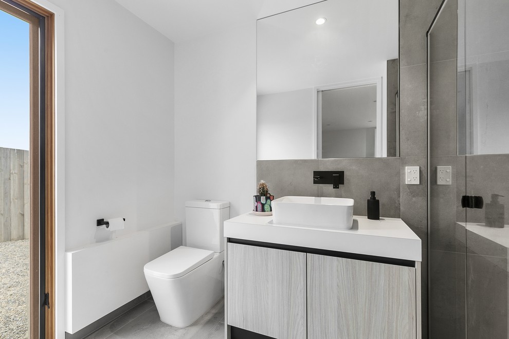 Photo of a contemporary bathroom in Geelong with flat-panel cabinets, light wood cabinets, a corner shower, a two-piece toilet, gray tile, cement tile, cement tiles, engineered quartz benchtops, grey floor, a hinged shower door, white benchtops and a vessel sink.