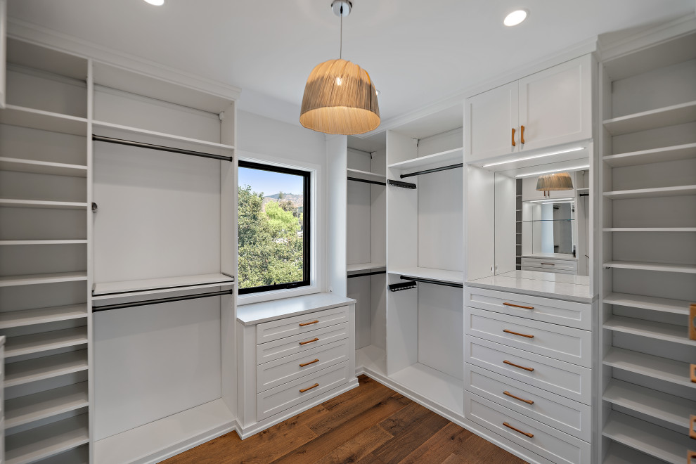 Photo of an expansive rural built-in wardrobe in Los Angeles with shaker cabinets, white cabinets, medium hardwood flooring and brown floors.
