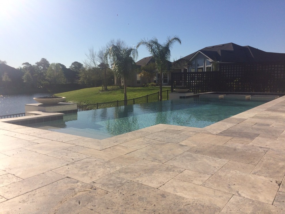Photo of a large transitional backyard rectangular infinity pool in Jacksonville with tile.